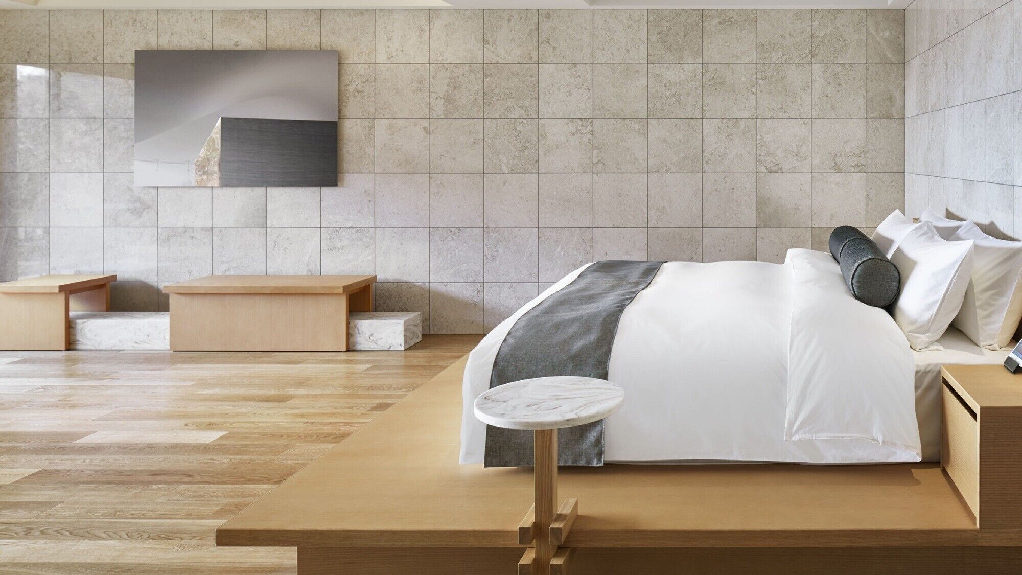 Ein modernes Schlafzimmer mit einem großen Bett, einem kleinen runden Tisch und einer Bank.