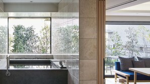 Een modern interieur met een groot raam, een bankje en een zithoek met kussens.