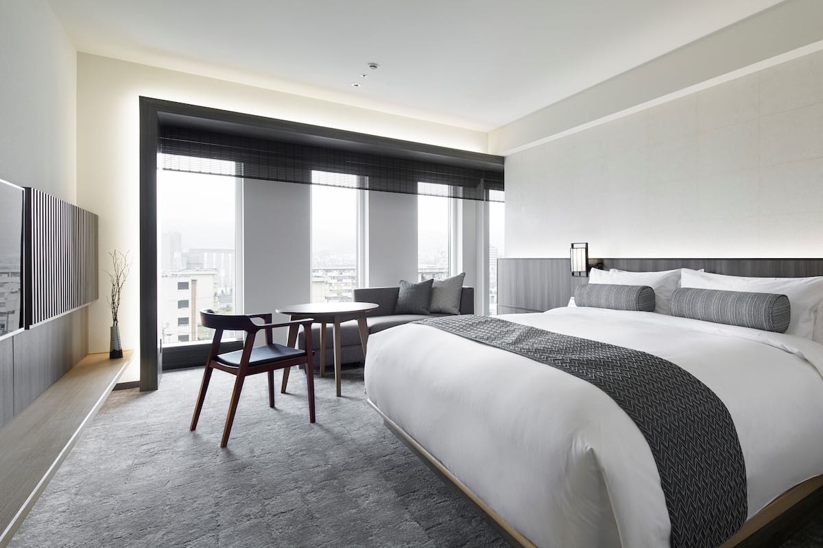 Habitación de hotel moderna con una cama grande, un escritorio y vistas a la ciudad.