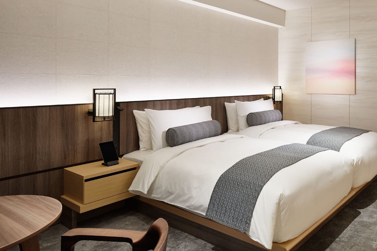 Una habitación de hotel moderna con una cama grande, mesitas de noche, un escritorio y una silla.