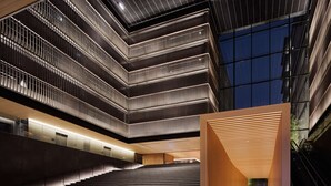 Een modern gebouw met meerdere verdiepingen, een centrale trap en een ruime open ruimte met houten constructie.