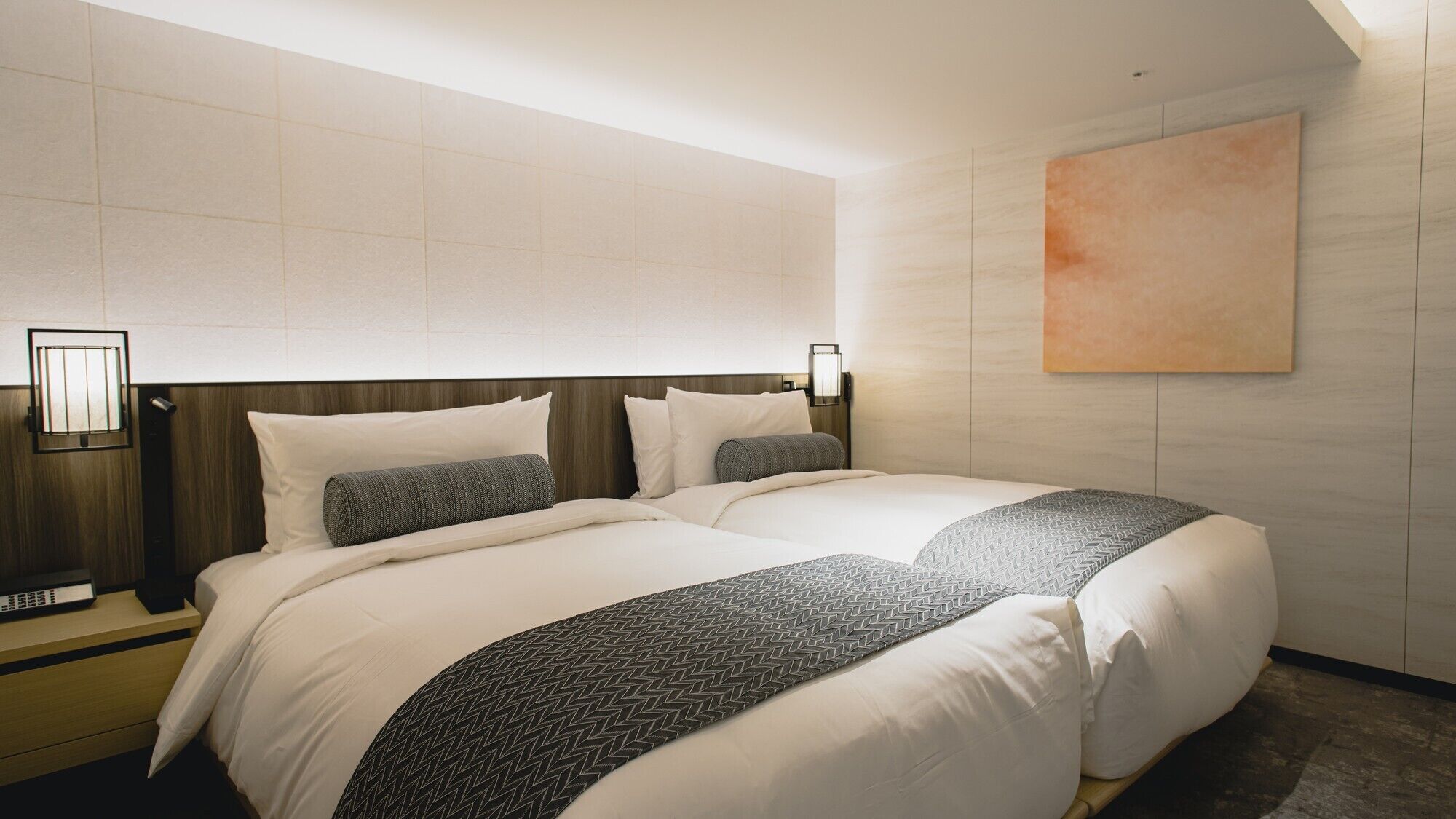 Ein Hotelzimmer mit einem großen Bett, einem Nachttisch, einer Wandleuchte und einem Gemälde.