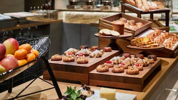 A buffet with various pastries, fruits, and cheeses.