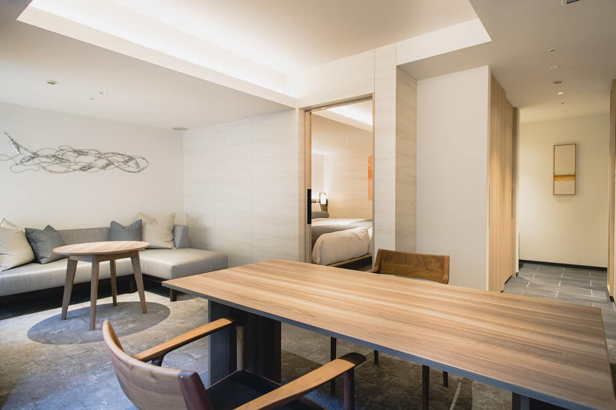 Un interior moderno con una mesa de comedor de madera, un sofá y una pequeña mesa redonda.