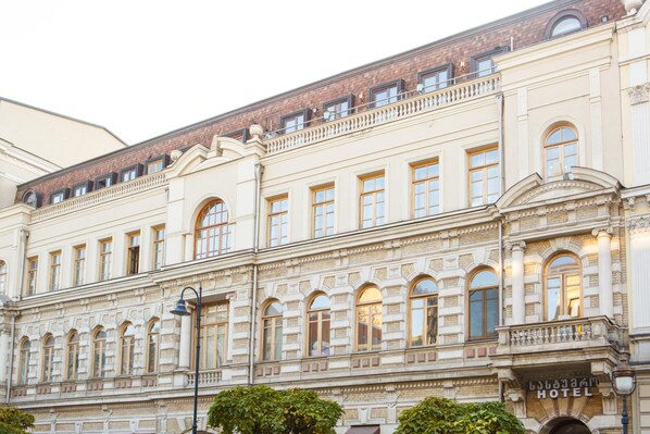 Un edificio histórico con múltiples ventanas, un balcón y un cartel que indica que es un hotel.