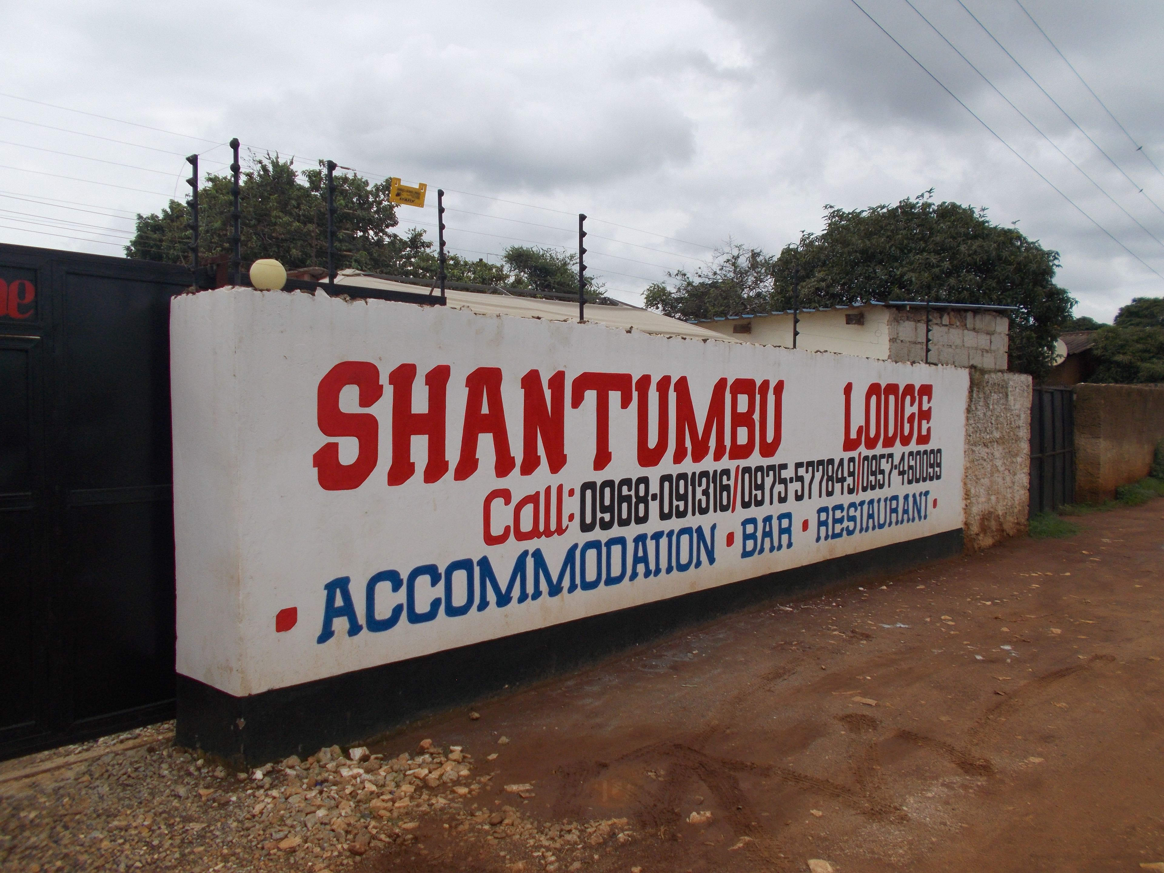 A sign for Shantumbu Lodge advertising accommodation, bar, and restaurant services.