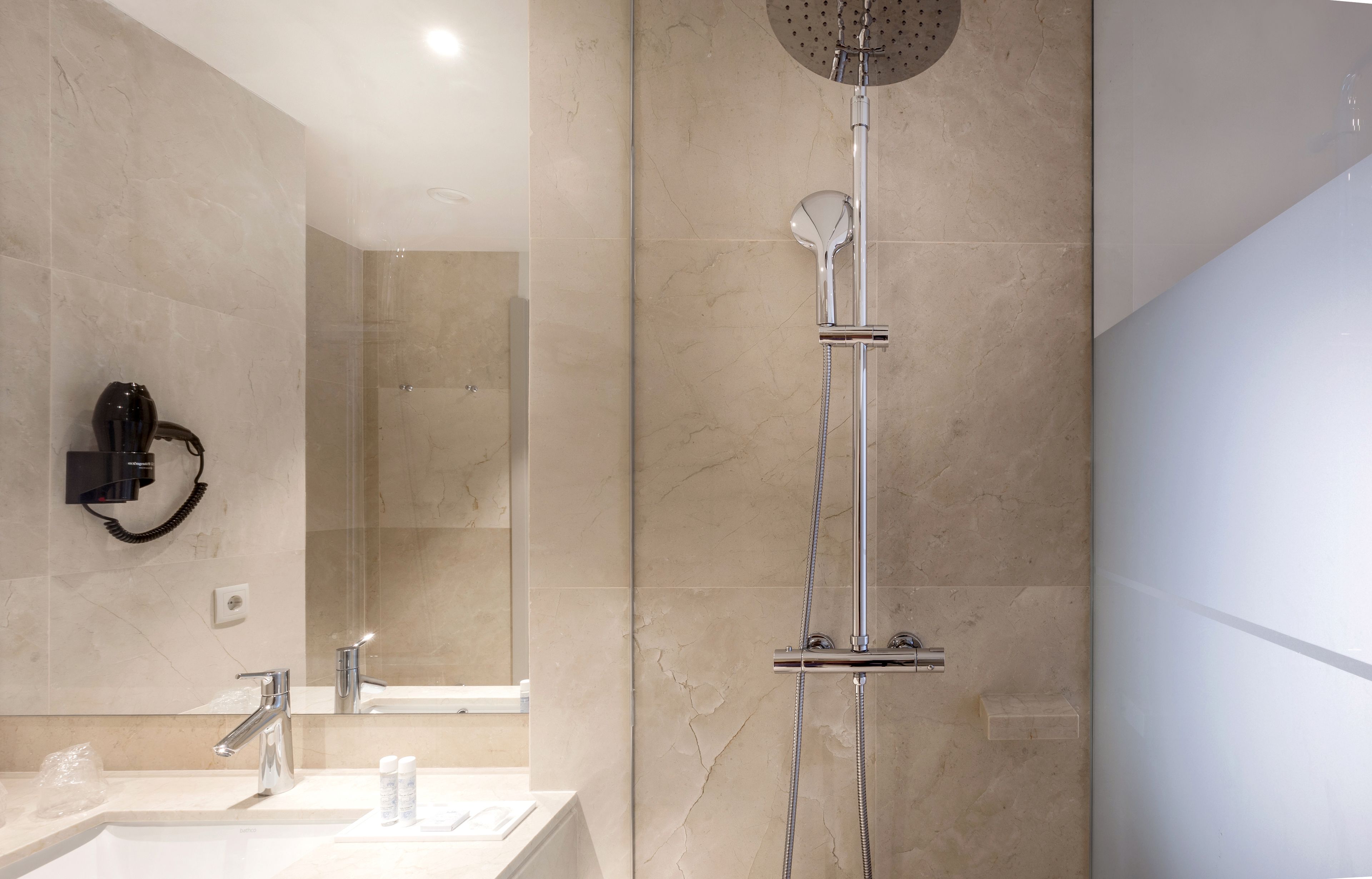 Ein modernes Badezimmer mit Dusche, Waschbecken und einem an der Wand befestigten Föhn.
