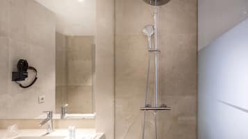 Un baño moderno con ducha, lavamanos y secador de pelo montado en la pared.