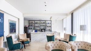 Un moderno vestíbulo de hotel con zona de bar, asientos cómodos y una barra de mármol.