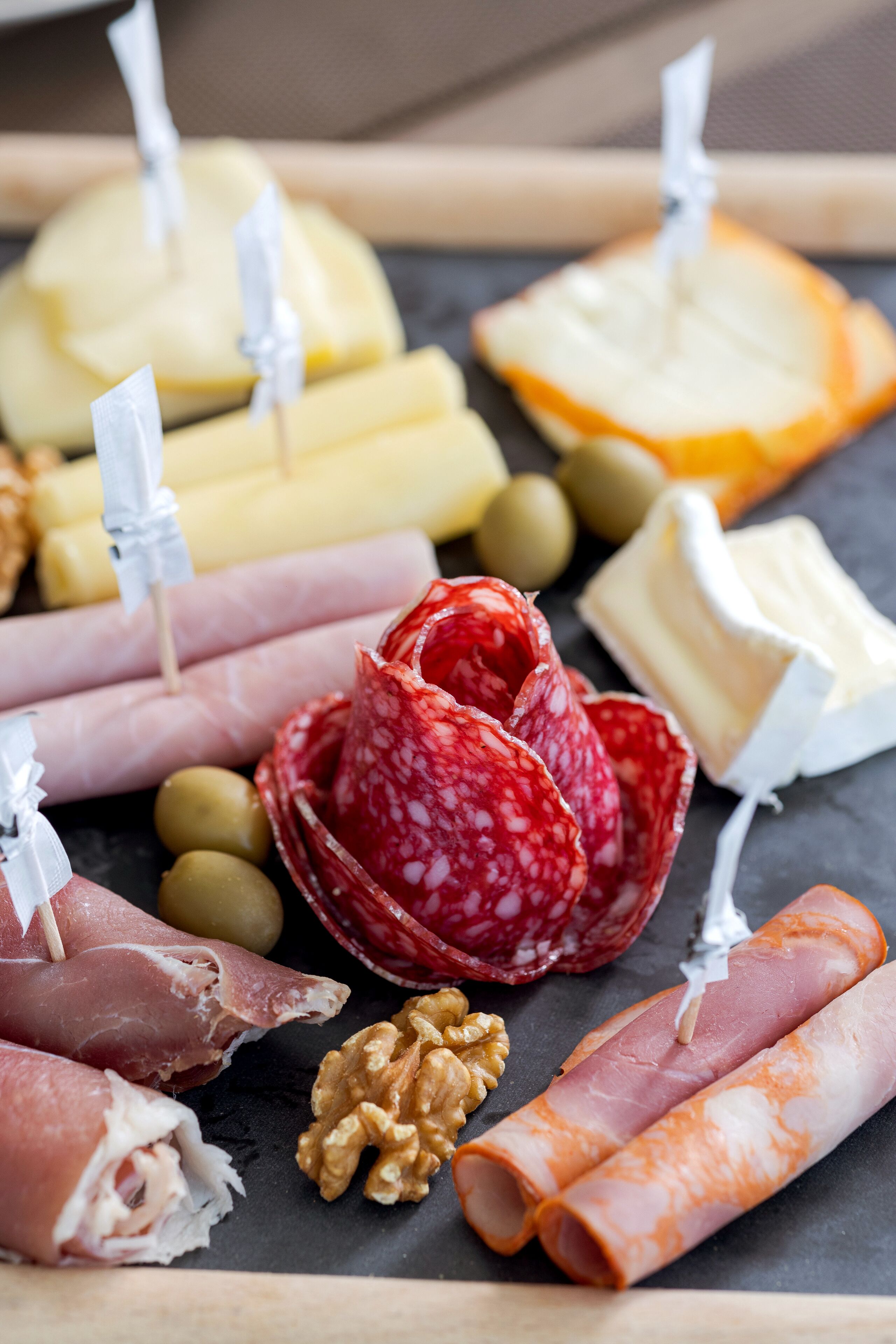 A charcuterie board with various meats, cheeses, and olives.