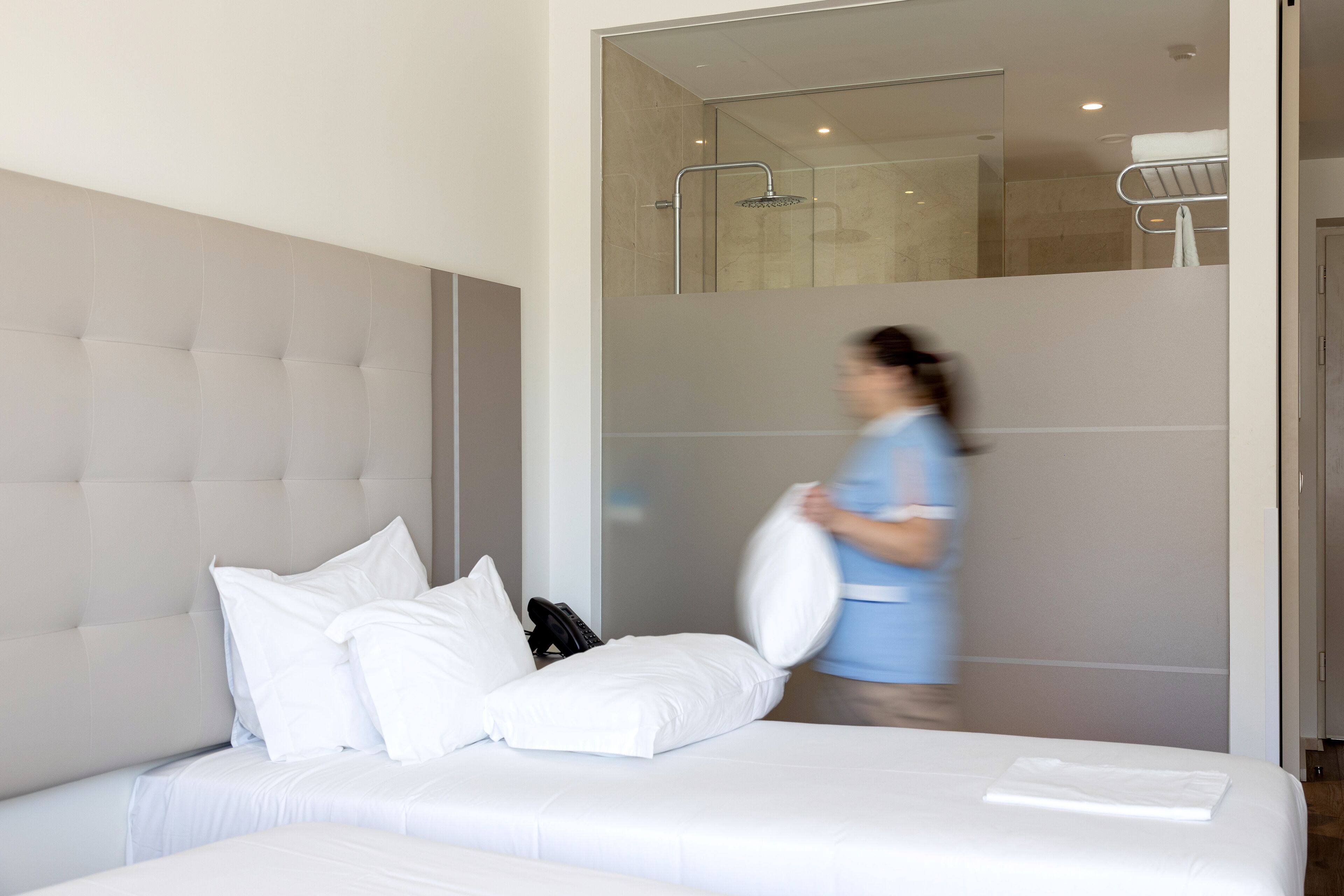 Habitación de hotel con una cama grande, cabina de ducha de vidrio y puerta de baño visible.