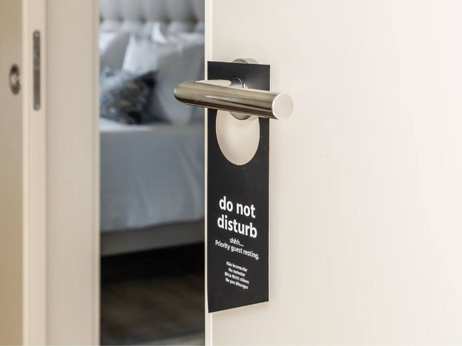 Puerta con un cartel de 'no molestar' y un picaporte metálico.