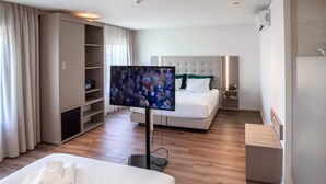 Una habitación de hotel con cama, televisor, armario y mesita de noche.