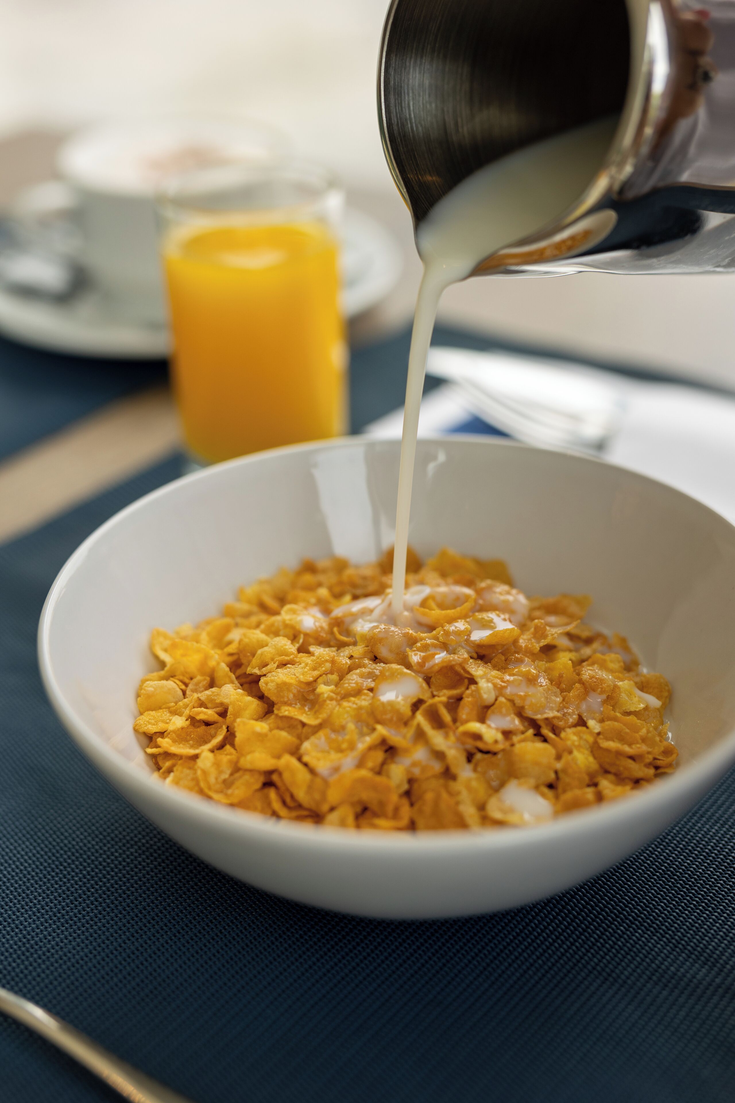 A bowl of cereal with milk being poured into it.