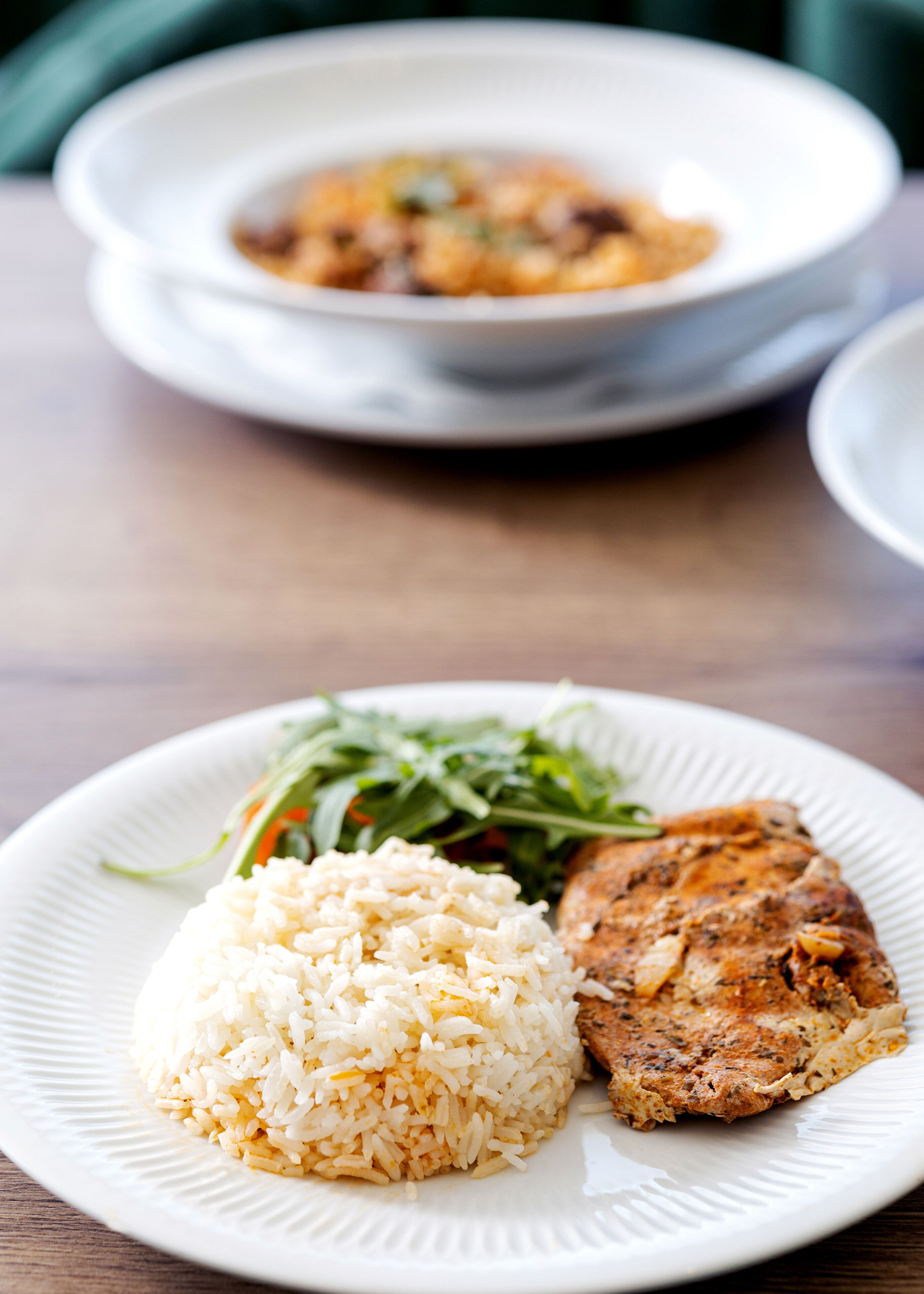 A plate with rice, a piece of grilled chicken, and a salad.