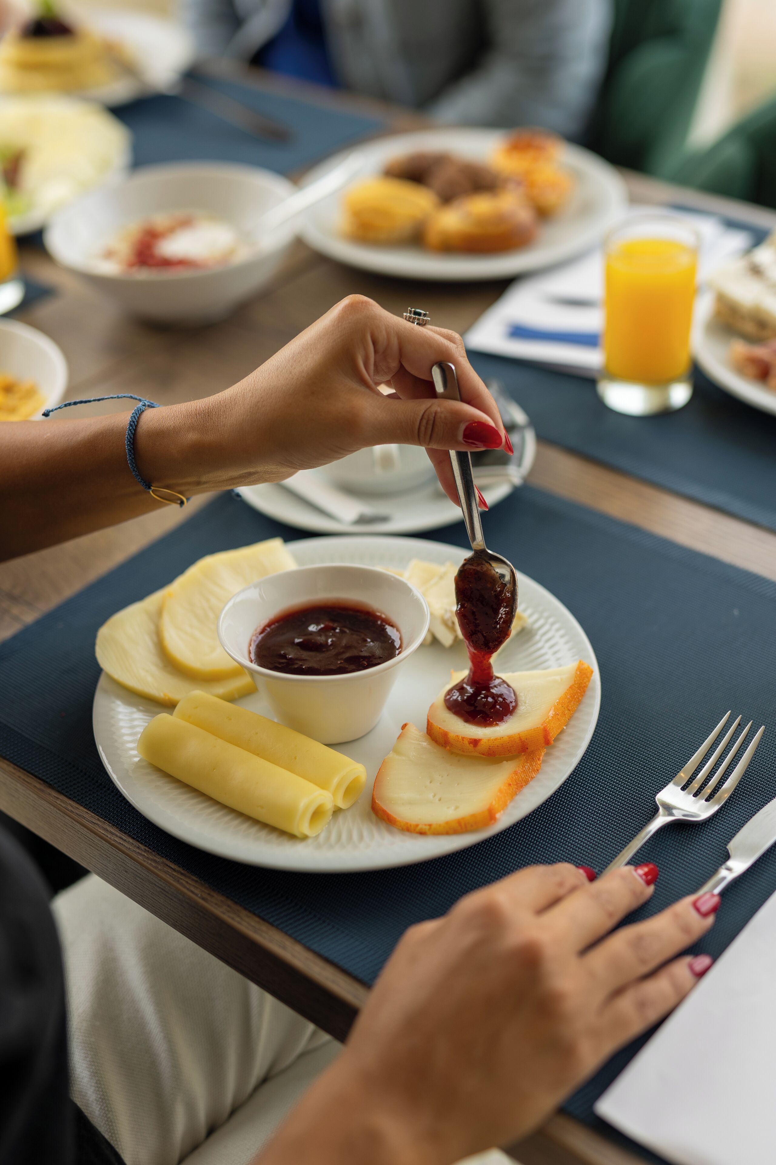 A dining table with a plate of food, including pancakes, a bowl of jam, and a glass of orange juice.