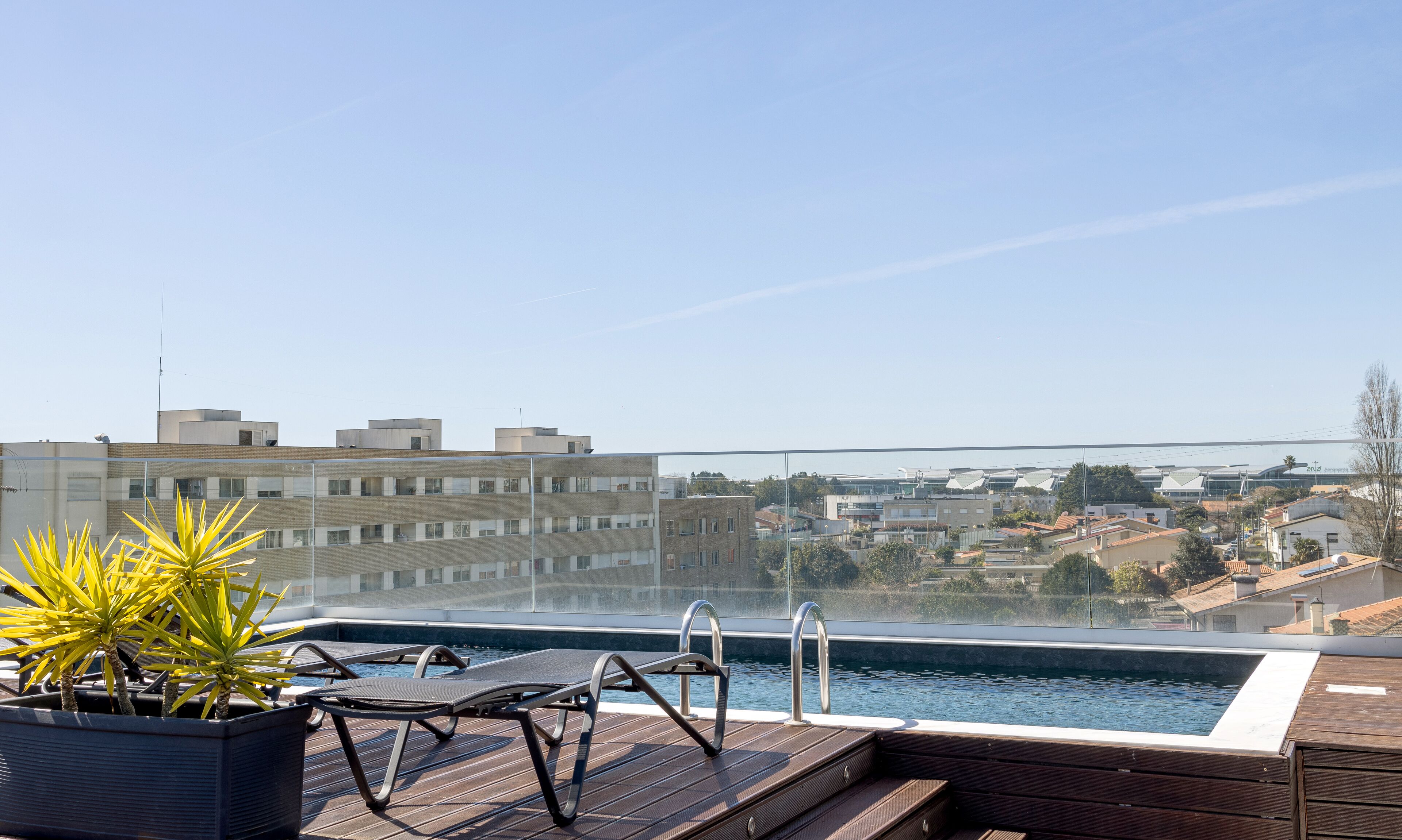A rooftop pool with lounge chairs and a view of the cityscape.