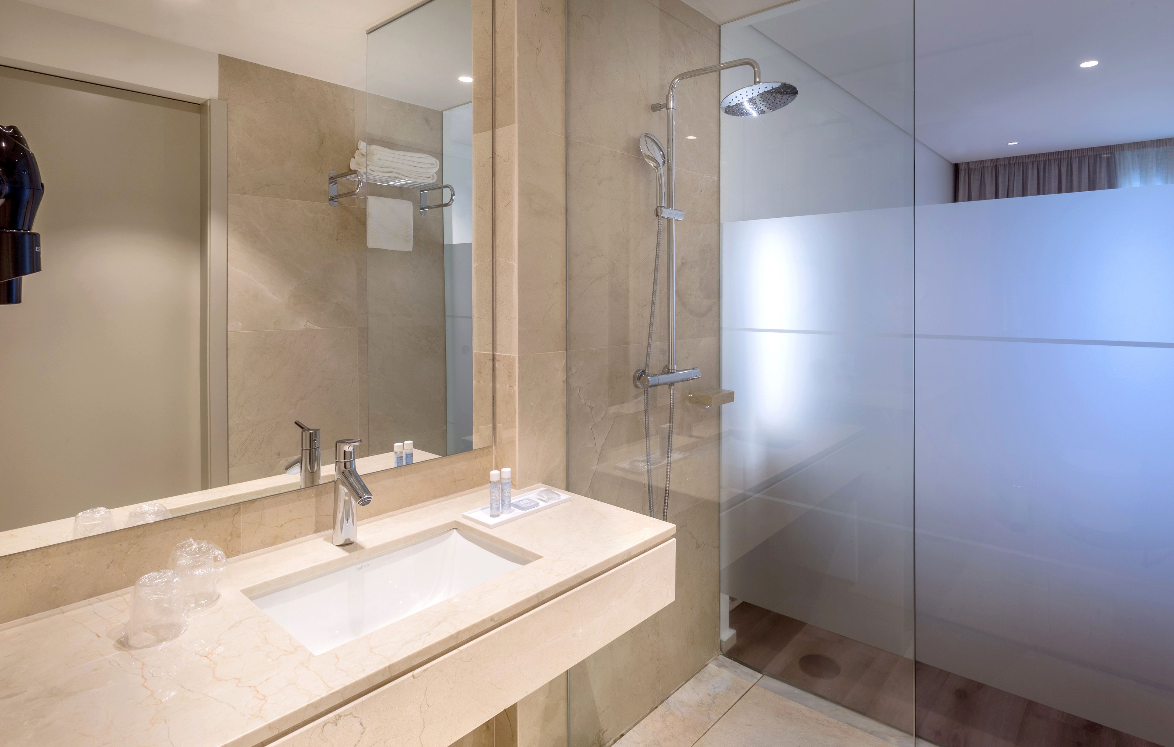A modern bathroom with a large mirror, two sinks, and a walk-in shower.