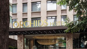 L’extérieur de l’hôtel Orchid se distingue par sa façade moderne, ses grandes fenêtres et son entrée imposante.