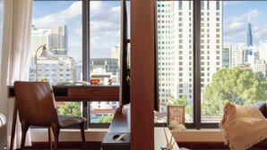 Un salon moderne doté d’une grande fenêtre, d’un plancher en bois, d’un bureau, d’une chaise et d’un canapé.
