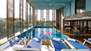 Une piscine sur le toit, avec une eau d’un bleu cristallin, entourée de chaises longues et d’un espace repas agrémenté de tables et de chaises.