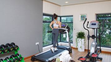Un gimnasio con cinta de correr, elíptica y mancuernas.