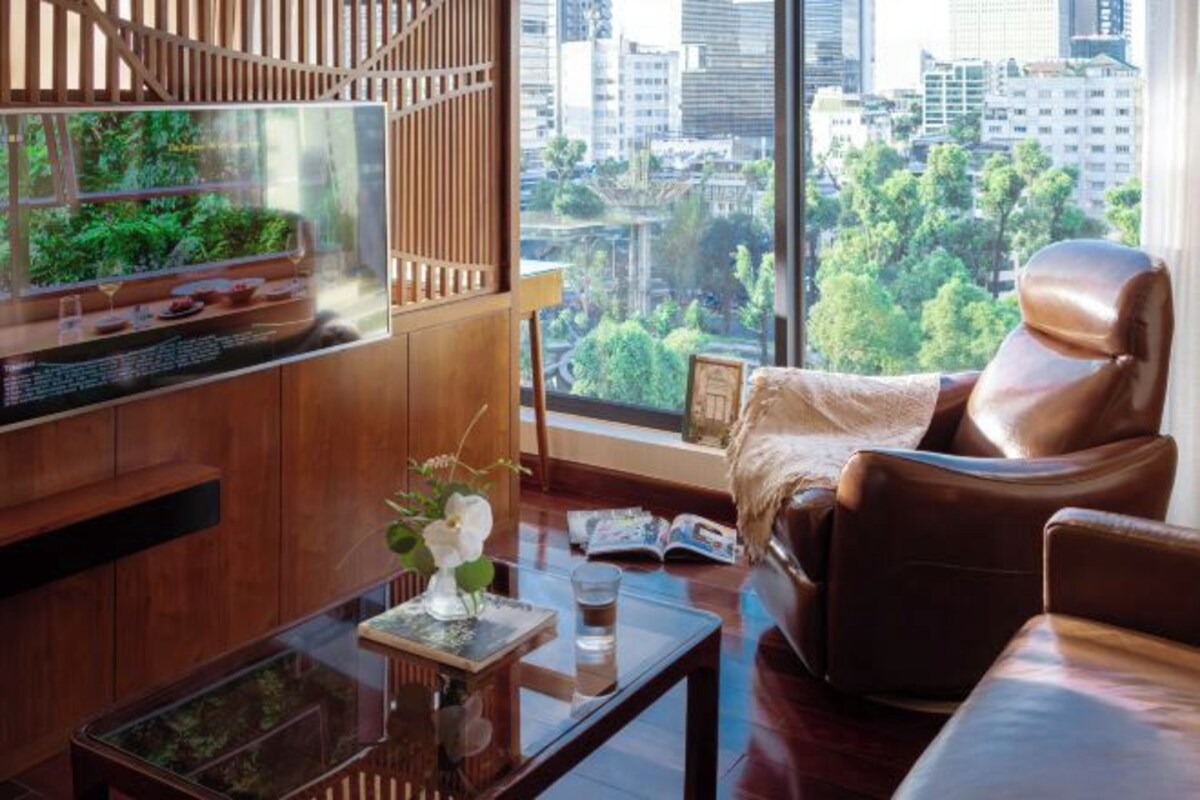 Un saló modern amb un aquari gran, un sofà de cuir i vista a un paisatge urbà a través de grans finestres.