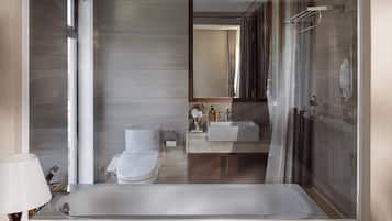 A modern bathroom with a large mirror, a bathtub, a toilet, and a sink.