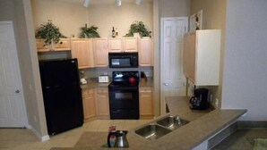 A compact kitchen with a refrigerator, stove, microwave, and sink. There are cabinets and a countertop. - Ly53805 - Terrace Ridge - 4 Bed 2 Baths Condo (Davenport)