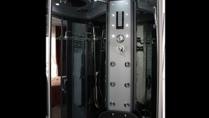Un baño moderno con cabina de ducha de vidrio, un panel de control con varios botones y una puerta de vidrio que da a un dormitorio.