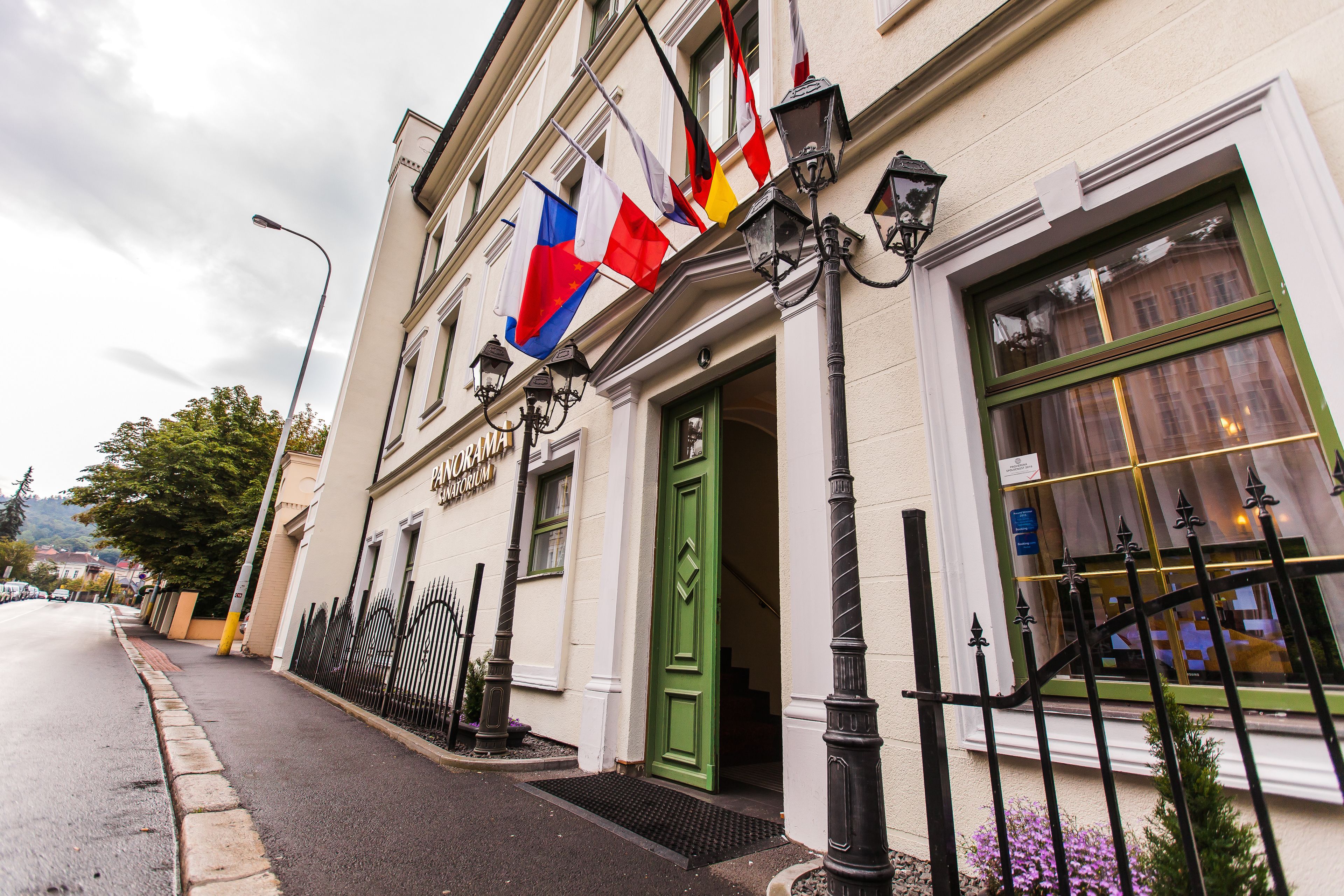 A building with a green door, multiple flags, and a street lamp.