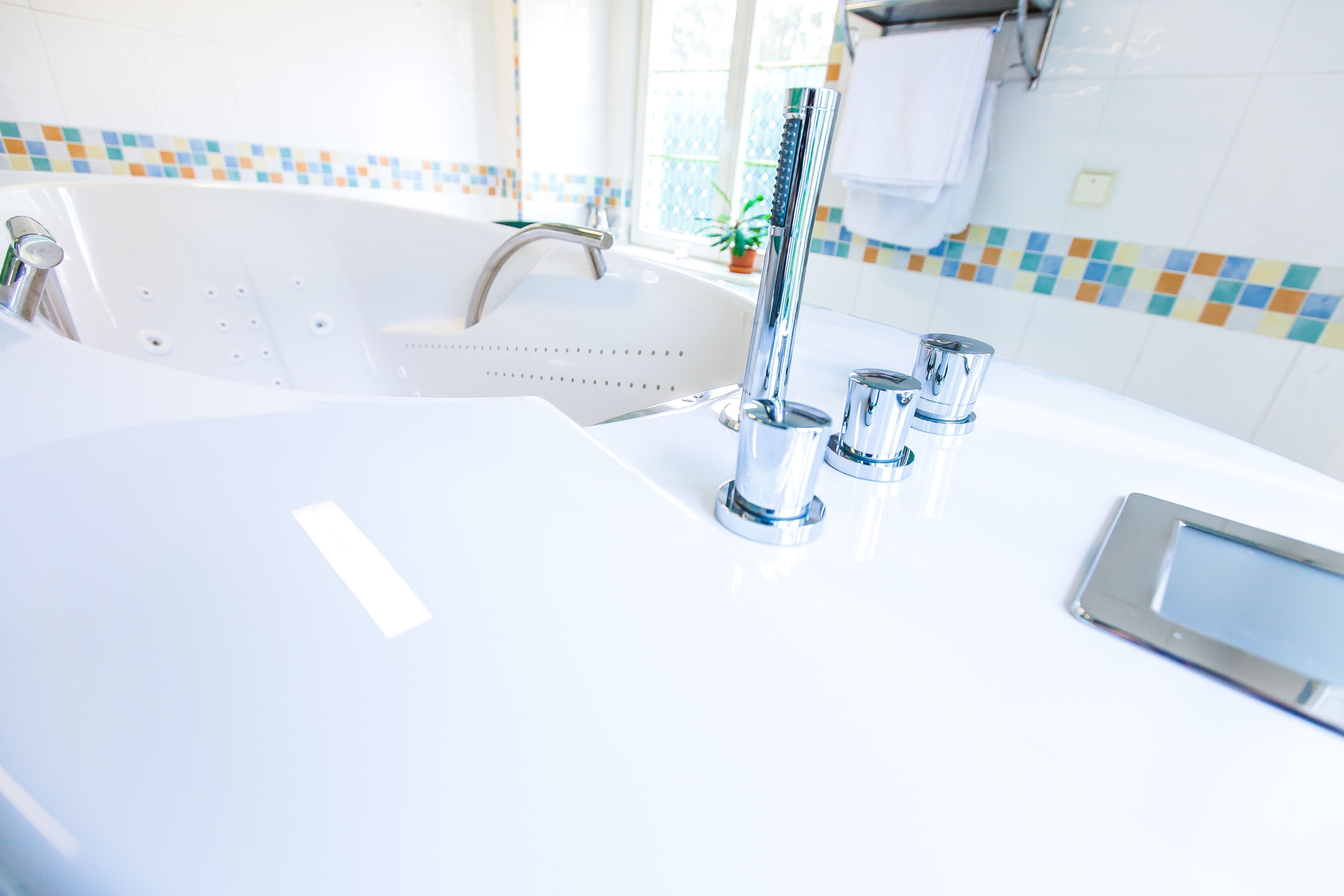 A modern bathroom with a white sink, chrome faucet, and a handheld showerhead.