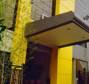 A building with a yellow and grey facade, a visible entrance, and a small balcony with a railing. - Castle Dreams Hotel (Davao)