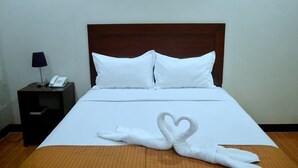 A hotel room with a neatly made bed, a bedside telephone, and a lamp on a nightstand. - Castle Dreams Hotel (Davao)