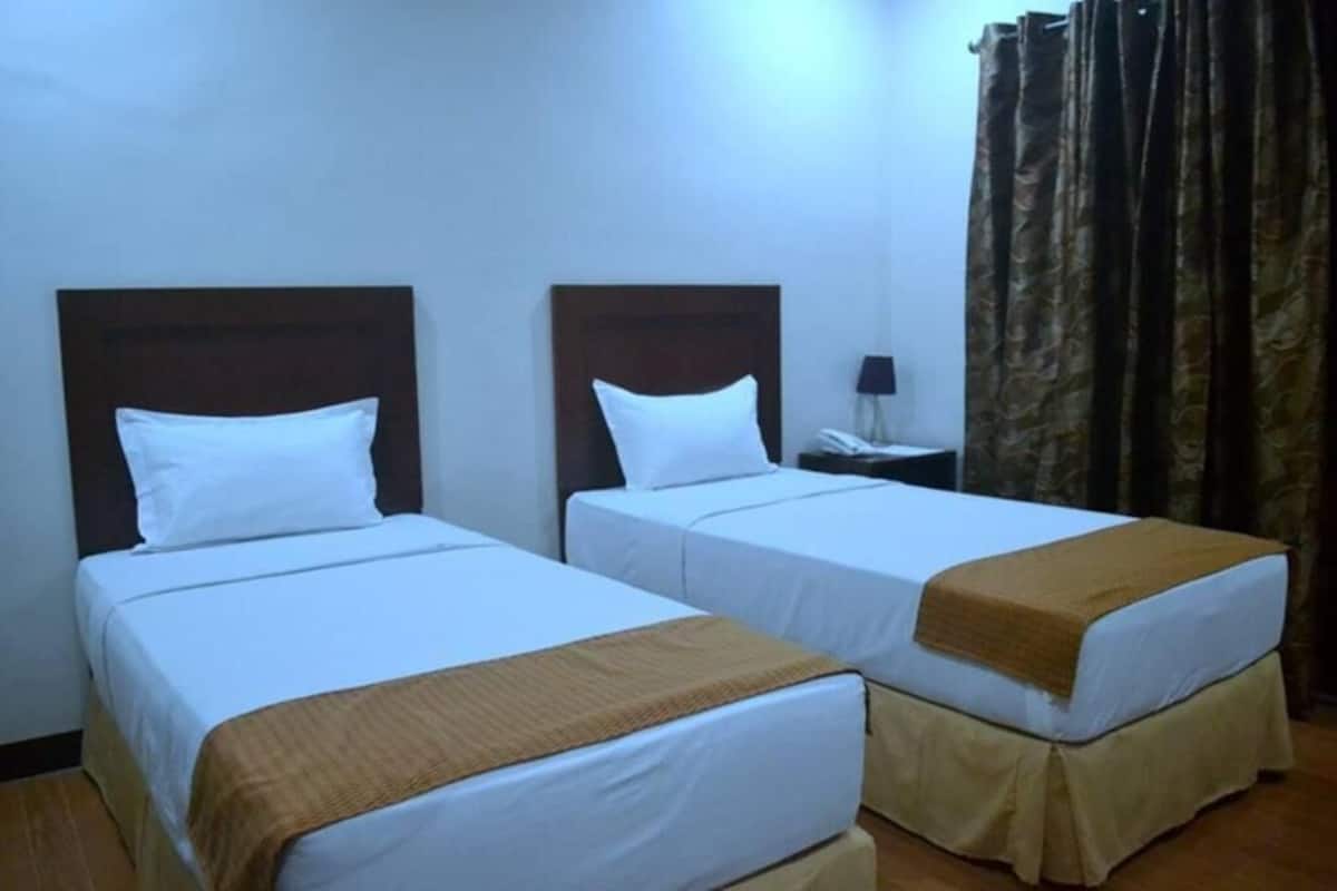 Two single beds with wooden headboards, white bedding, and a brown throw blanket.