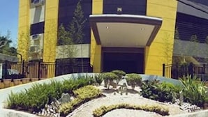 A building with a central entrance, surrounded by a landscaped area with plants and a pathway. - Castle Dreams Hotel (Davao)
