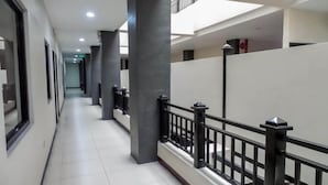 A corridor with a tiled floor, black railings, and a series of columns. - Castle Dreams Hotel (Davao)
