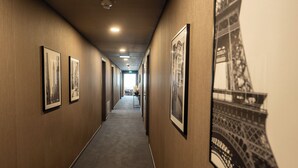A hallway with framed pictures on the walls, a carpeted floor, and a large image of the Eiffel Tower on the right wall. - V Boutique Hotel (Boeblingen)