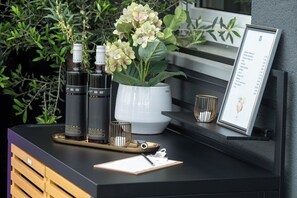A reception desk with a clipboard, two wine bottles, a vase with flowers, and a framed menu. - V Boutique Hotel (Boeblingen)