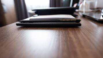 A wooden table with a black notebook and a pen labeled 'BOUTIQUE HOTEL' on it.