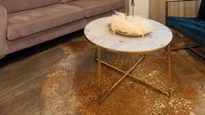 A modern living room with a beige sofa, a round coffee table with a white shag rug, and a decorative wall piece. - V Boutique Hotel (Boeblingen)