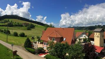 Un village rural avec un bâtiment remarquable, reconnaissable à son toit rouge, entouré de champs verdoyants et sous un ciel dégagé.
