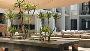 A modern living area with a concrete island, wooden stools, and palm plants. - Cavo Vezal - Adults Only (Zakynthos)