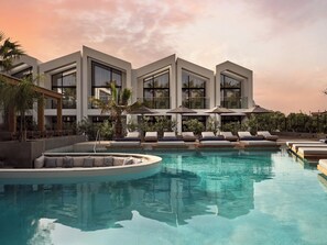 A modern hotel with a pool, lounge chairs, and umbrellas. - Cavo Vezal - Adults Only (Zakynthos)