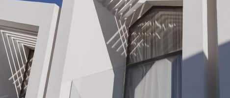 A modern building with a geometric facade and a balcony with a railing.
