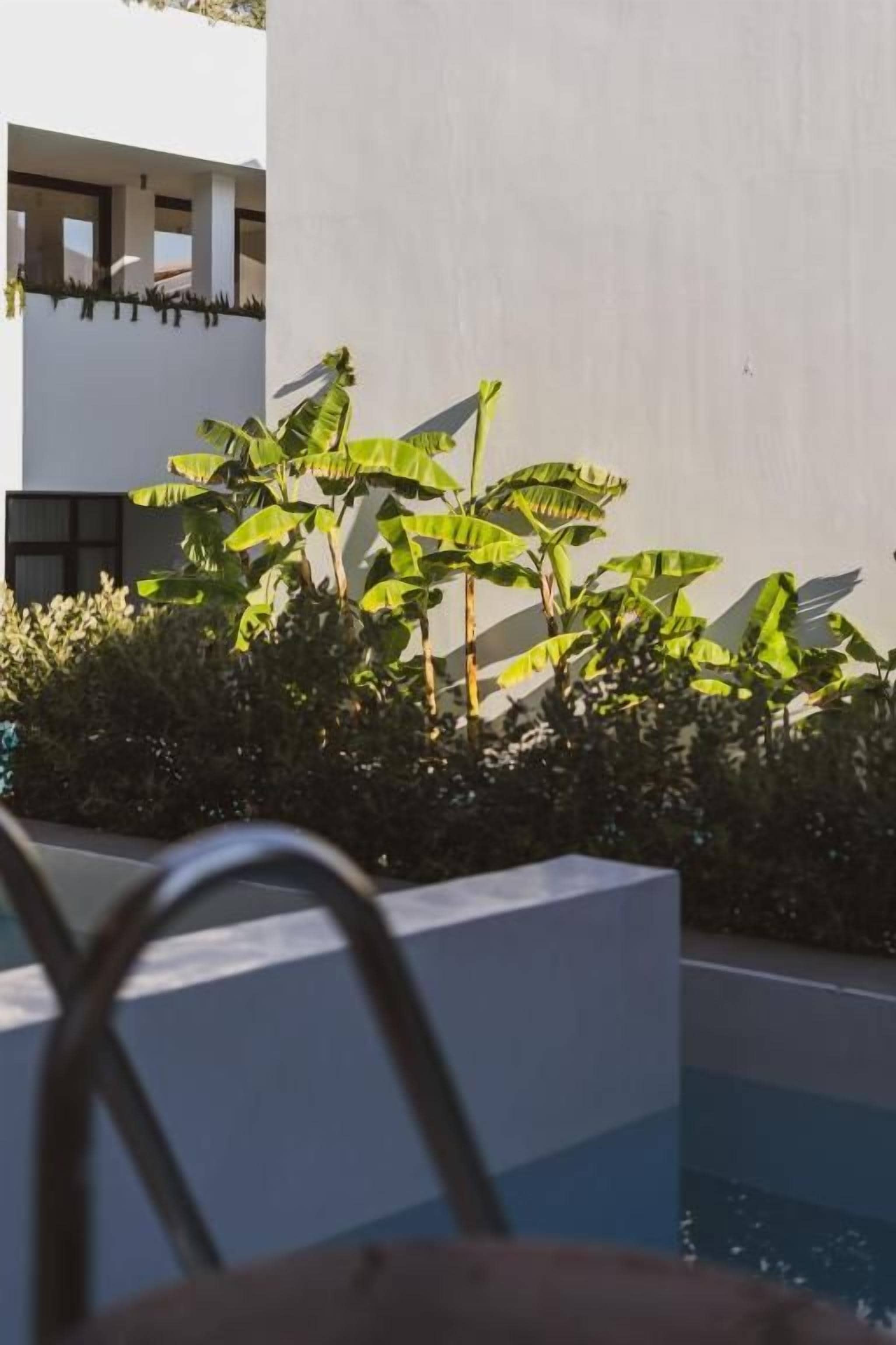 Un área de piscina con una pared blanca y una silla metálica al frente.
