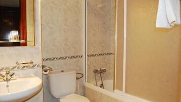 Un baño con lavamanos, inodoro y zona de ducha.