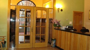 Un área de recepción con un mostrador de madera, un jarrón de flores y un cuadro en la pared.
