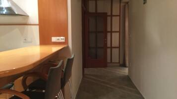 A hallway with a wooden table and chairs, a door with a glass panel, and a light switch on the wall.