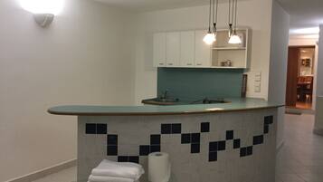 Una cocina moderna con encimera verde azulada, armarios blancos y salpicadero de azulejos.
